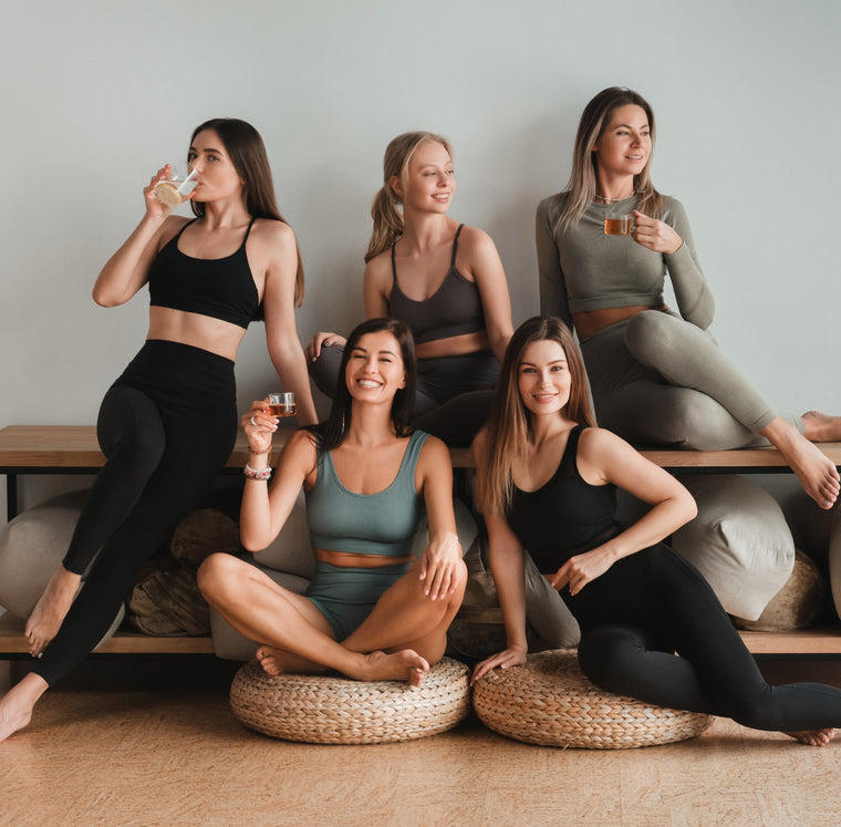 Five fitness women are smiling at the camera.